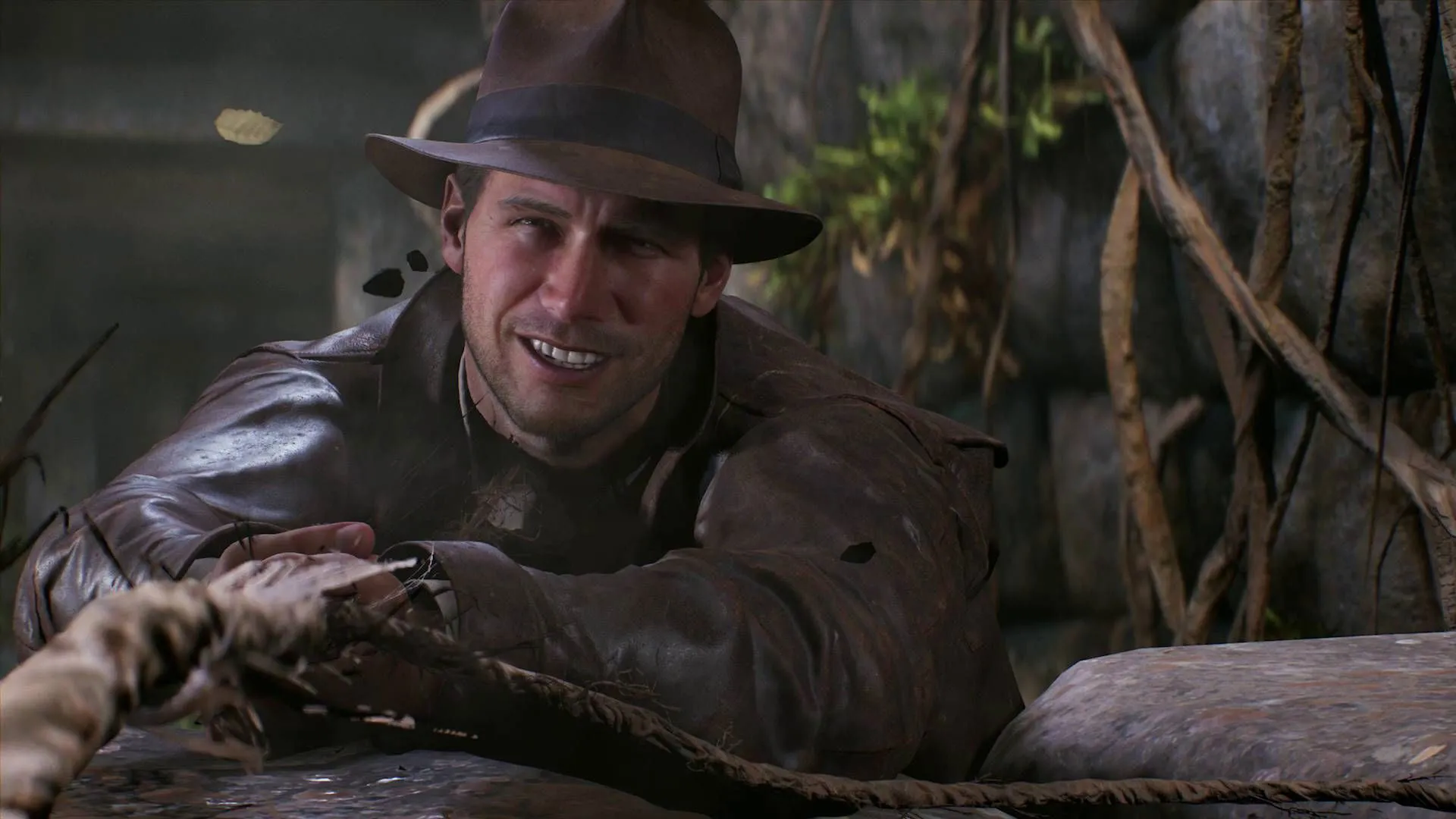 Captura Indiana Jones And The Great Circle – Indy Tenso Se Agarra A Una Cuerda Colgante Mientras Barro Y Vegetacion Cubren El Fondo