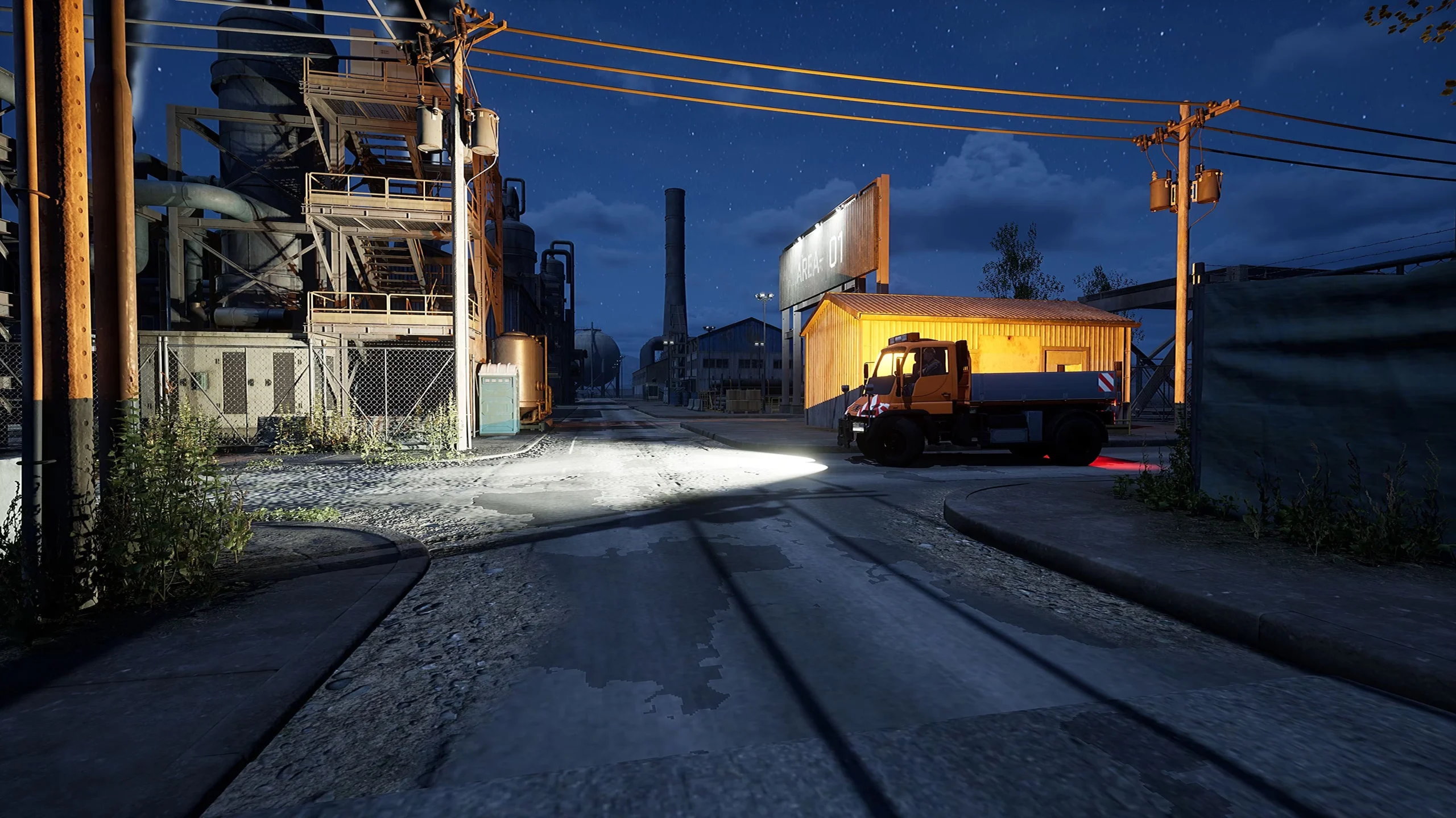 Captura Oil Refinery The Simulation – Vehiculo Industrial Iluminado Frente A Una Caseta Naranja Dentro De Una Planta De Refinado Nocturna Scaled