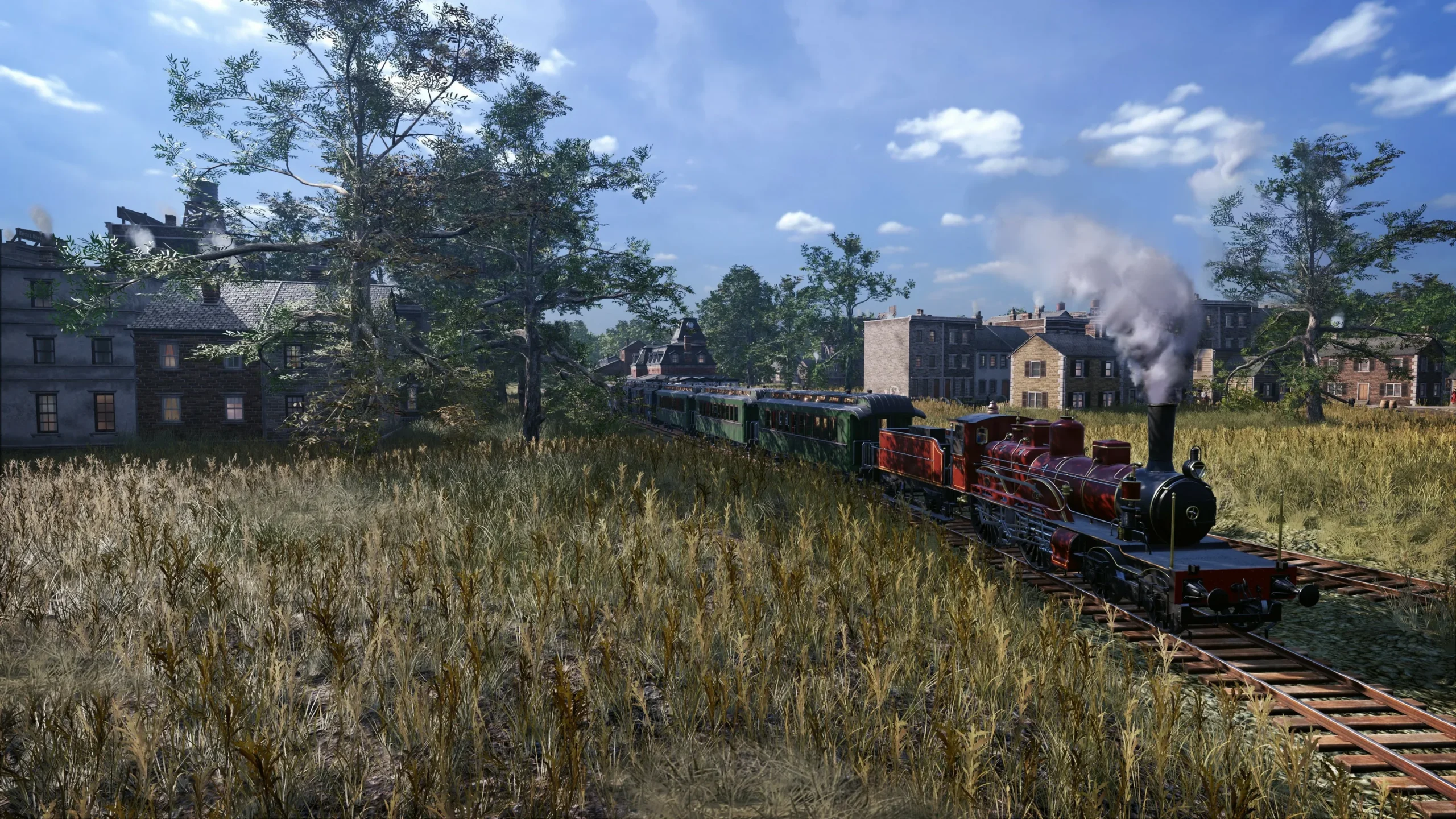 Captura Railway Empire 2 – Un Tren Rojo Se Desplaza Por Un Campo Abierto Con Casas Al Fondo Bajo Un Cielo Despejado Scaled