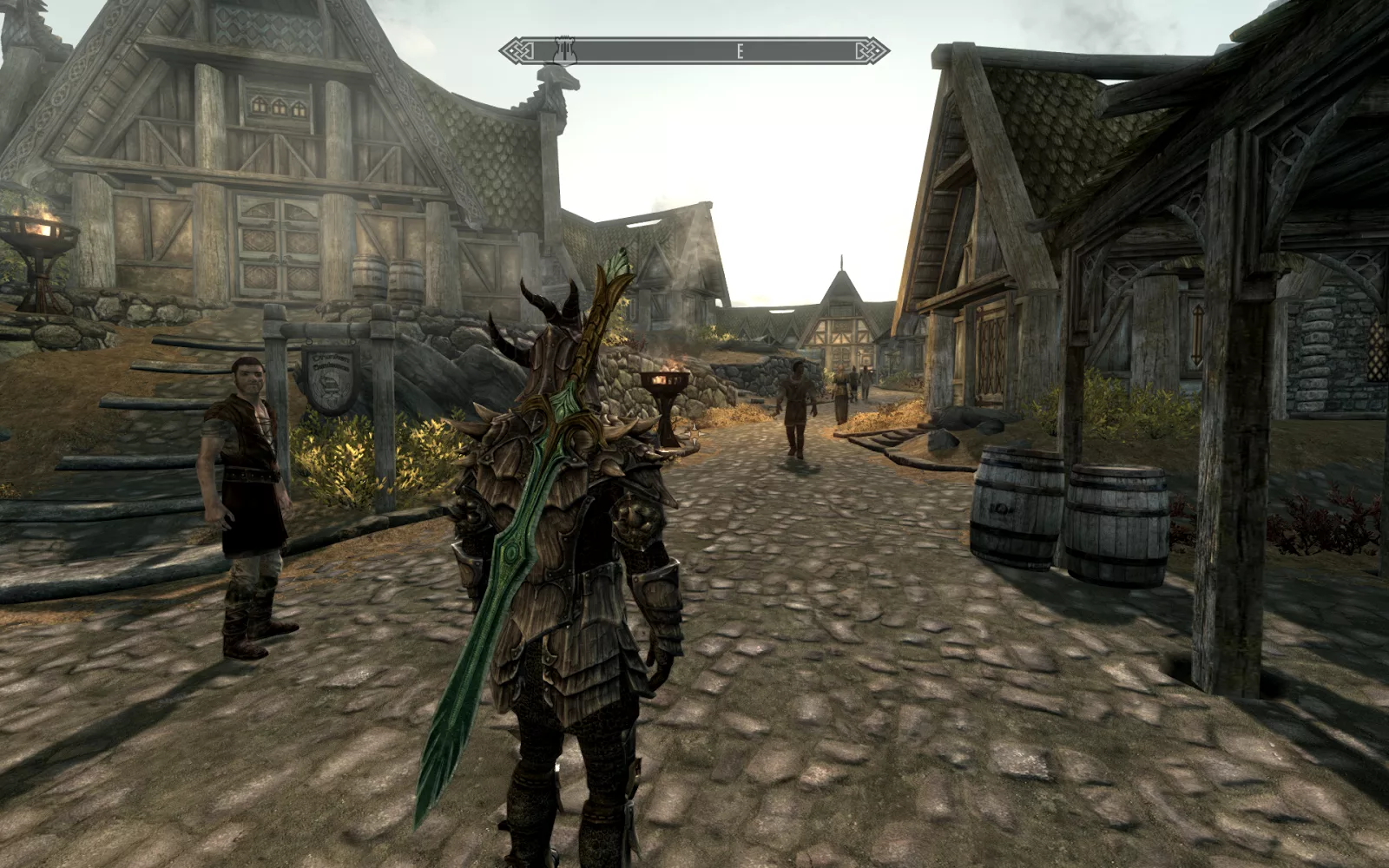 Captura The Elder Scrolls V Skyrim Legendary Edition – Personaje Con Armadura Y Espada En La Espalda Caminando Por Un Pueblo Medieval Empedrado