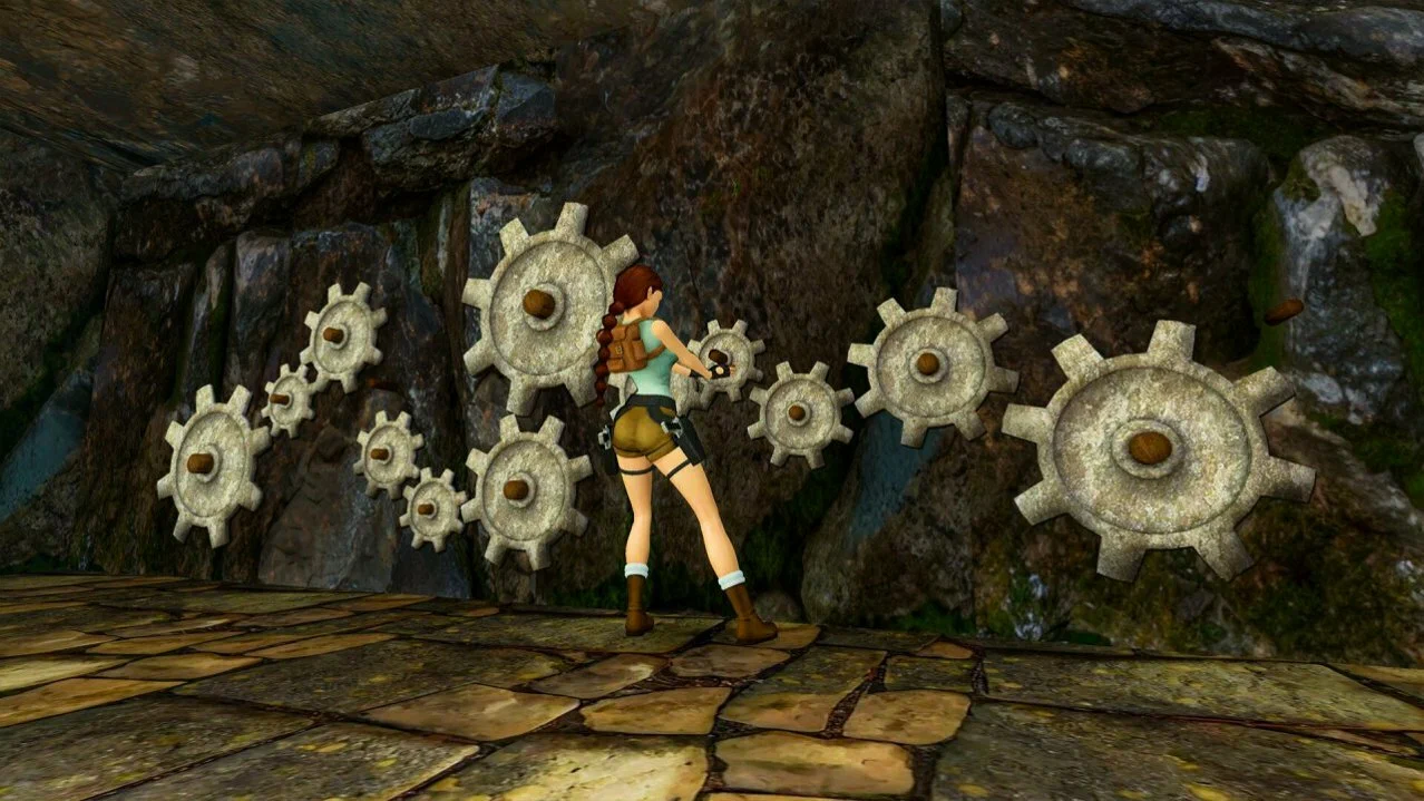 Captura Tomb Raider I–II–III Remastered – Lara Manipula Engranajes De Piedra Incrustados En Una Pared De Cueva